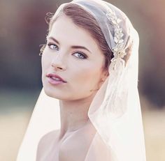 a woman wearing a veil with flowers in her hair is looking off to the side