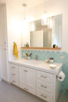 a bathroom with white cabinets and blue scalloped wall paper on the back splash