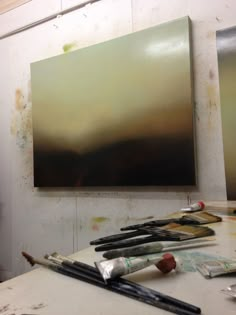 the painting is being displayed on the easel in the room with it's paintbrushes and palettes