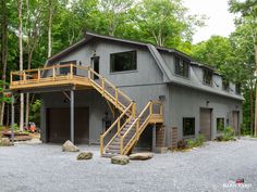 a two story house with stairs leading up to the front door and second story garage