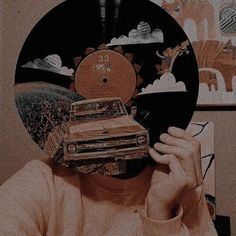 a person holding up a record with a car on it's face in front of them