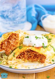 an enchilada on a plate with sour cream