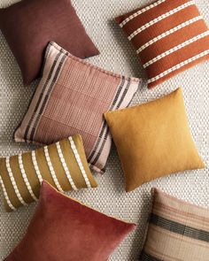 many different colored pillows on a white surface