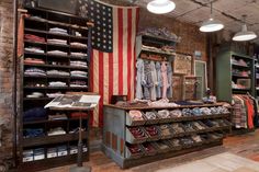 the inside of a clothing store with an american flag hanging from the ceiling and clothes on shelves