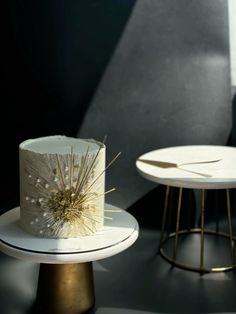 a white cake sitting on top of a table next to a side table with two plates