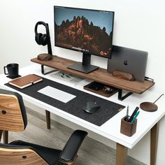 a computer desk with two monitors, keyboard and headphones on it in front of a white wall