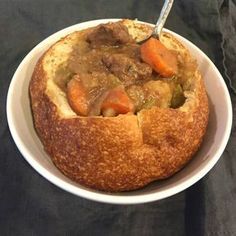 a bowl filled with meat and vegetables on top of a black table next to a fork