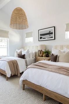 two beds in a bedroom with white linens and pillows