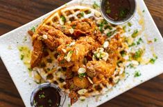 fried chicken and waffles on a white plate with dipping sauce next to it