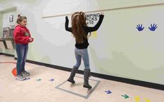 two girls standing in front of a whiteboard with writing on it and hand prints