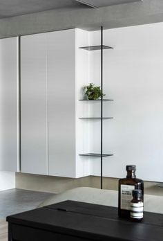 an empty room with shelves and bottles on the table in front of it, next to a wall mounted planter