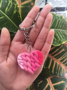 a hand holding a pink heart shaped keychain with a chain attached to it