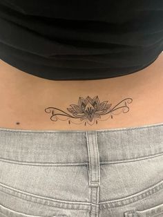 a woman's stomach with a lotus tattoo on her lower back and the word, i