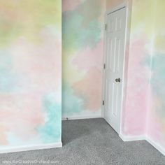 an empty room with pastel paint on the walls and carpeted floor in front of a white door