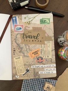 an open travel journal sitting on top of a wooden table next to some crafting supplies