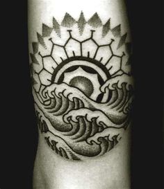 a black and white photo of a tattoo on someone's leg with waves in the background