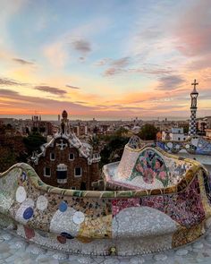 an artisticly designed bench on top of a hill overlooking the city at sunset or dawn