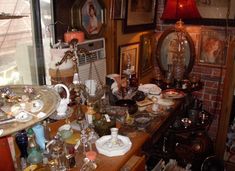 a room filled with lots of clutter on top of a wooden table next to a window