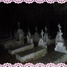 an old cemetery with many headstones and crosses in the grass, at night time