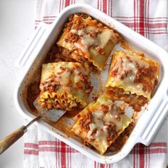 lasagna casserole with meat and cheese in a white dish on a red and white checkered tablecloth