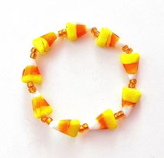 a yellow and white beaded bracelet on a white surface with orange beads around it