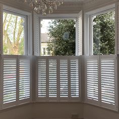 an empty room with white shutters and chandelier