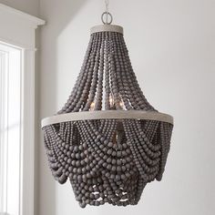 a chandelier made out of beads hangs from the ceiling in a white room