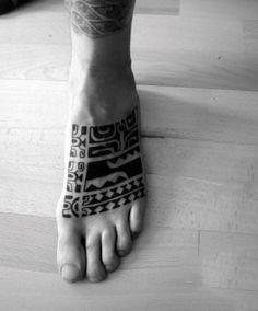 a black and white photo of a person's foot with an intricate tattoo on it