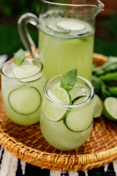 three glasses filled with cucumber water on a wicker tray next to green beans