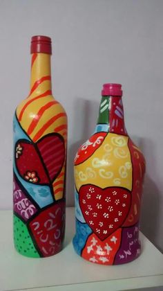 two colorful painted bottles sitting on top of a white shelf next to each other,