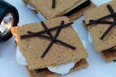 some crackers with sticks sticking out of them on a white plate next to a flashlight