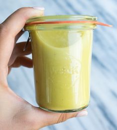 a hand holding a glass jar filled with green liquid