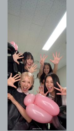 group of women posing with balloons in front of their faces and hands up to the camera