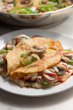 two white plates topped with food next to a pan filled with mushrooms and green peppers