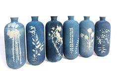 five blue vases with white designs on them are lined up against a white background