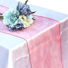 a bouquet of blue and white flowers sitting on top of a pink table cloth covered table