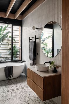 a bath room with a tub a sink and a large mirror on the wall next to a window