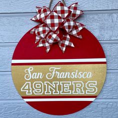 a red and white sign with a bow hanging from it's side on a wall