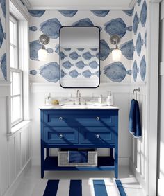 a blue and white bathroom with fish wallpaper on the walls, two sinks and a mirror