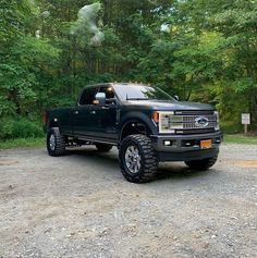 a large black truck parked in front of some trees