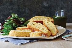 some bread is on a white plate next to a salad