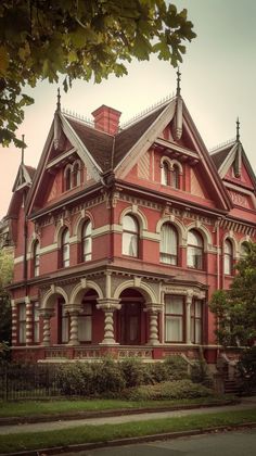 an old red brick house with white trim and windows on the top floor, in front of a tree