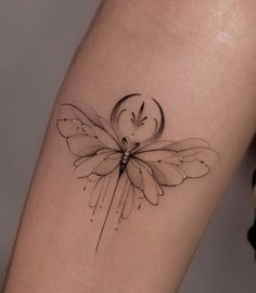 a black and white photo of a butterfly tattoo on the right thigh, with an arrow in the middle