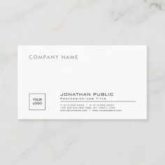 a white business card with a black and gray logo on it, sitting on a marble surface