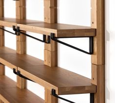 the shelves are made out of wood and have black metal brackets on each shelf,