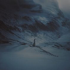 a person standing on top of a snow covered mountain under a cloudy sky at night