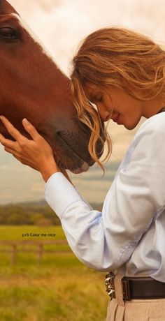 a woman is kissing a horse on the nose