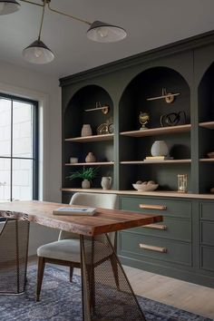 a dining room table with chairs and shelves on the wall behind it in front of a large window