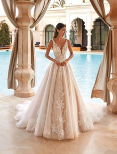 a woman standing in front of a pool wearing a wedding dress