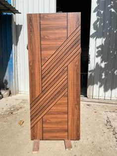 a large wooden door sitting on top of a cement floor next to a metal building